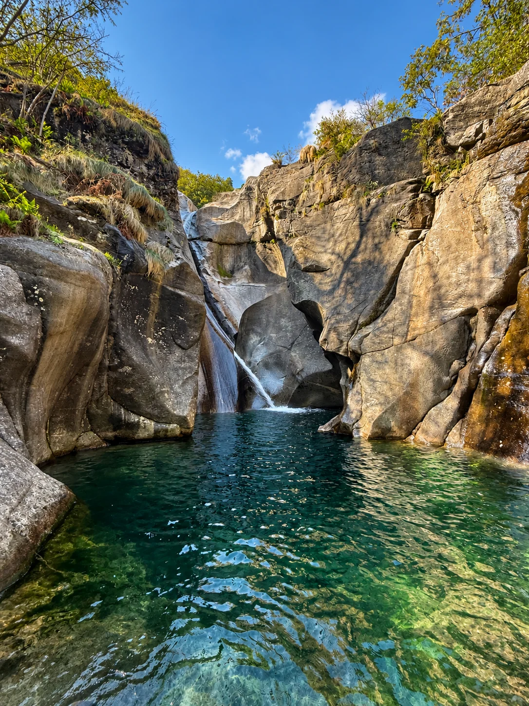 Wasserfall und klares grünes Wasser zwischen Felswänden